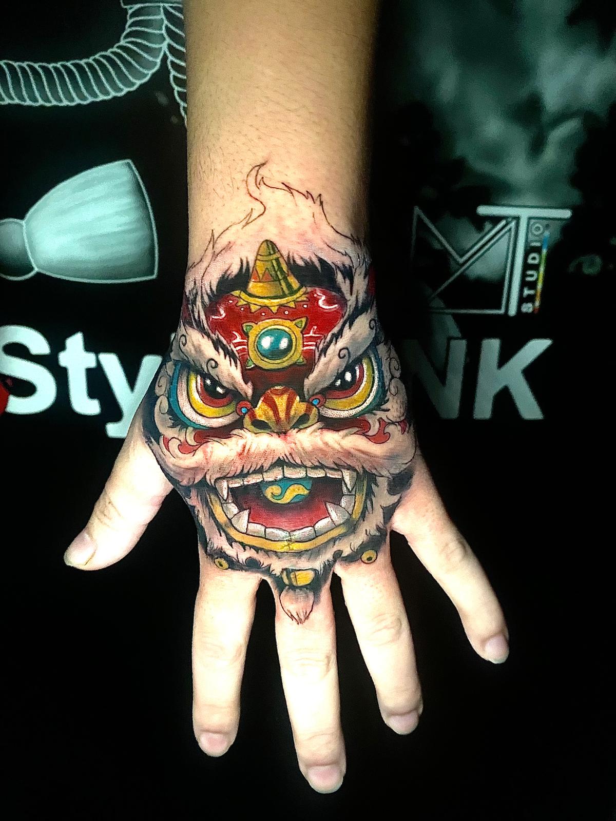 Tête de lion chinois sur la main — tatouage asiatique réalisé chez 3StylesINK